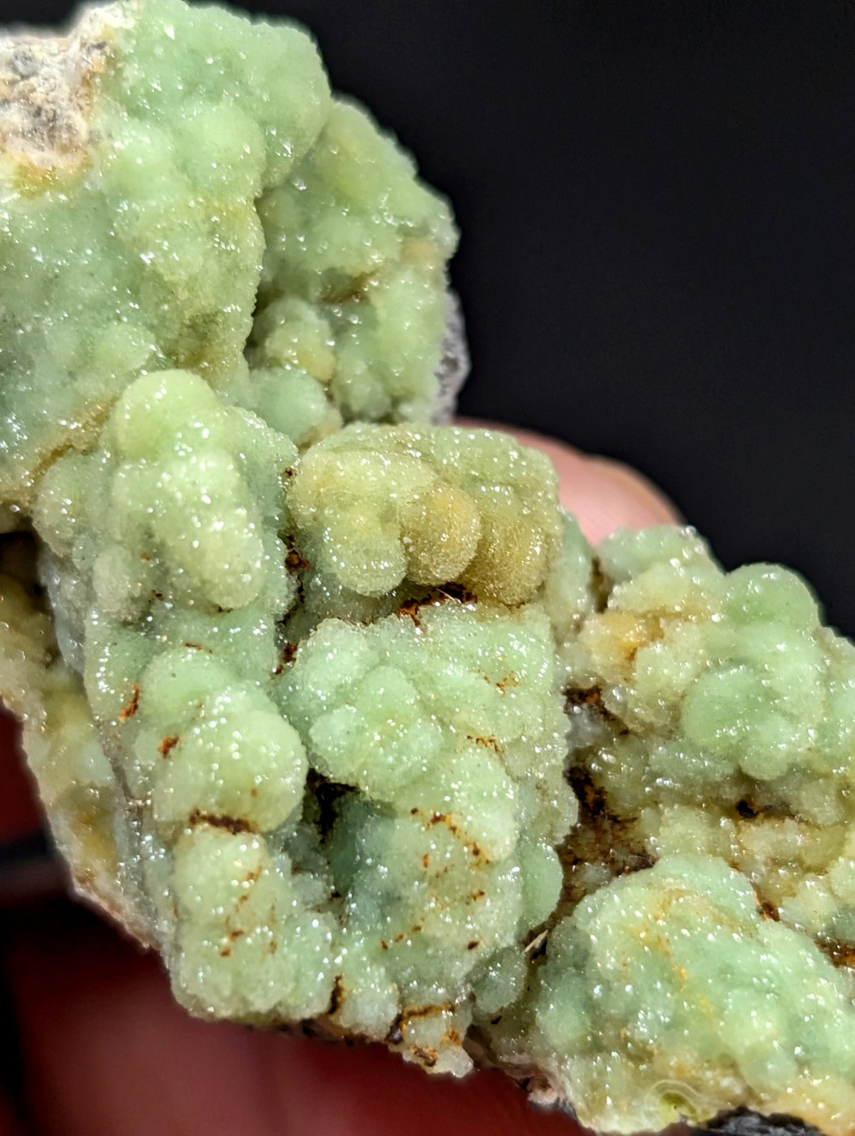 A cluster of pale green, crystalline minerals with a textured, bubbly surface and subtle golden-brown veining.