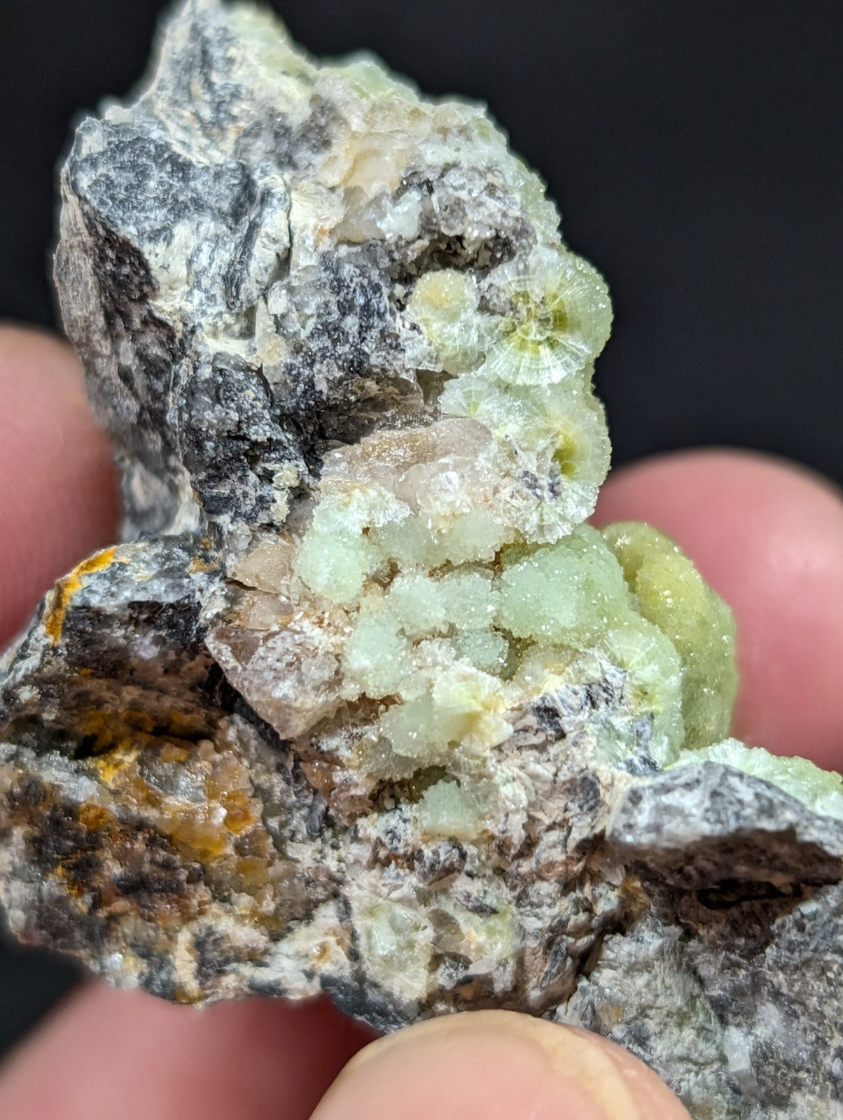 A rough, irregularly shaped mineral specimen featuring translucent green crystals growing from a dark gray and white rocky matrix.