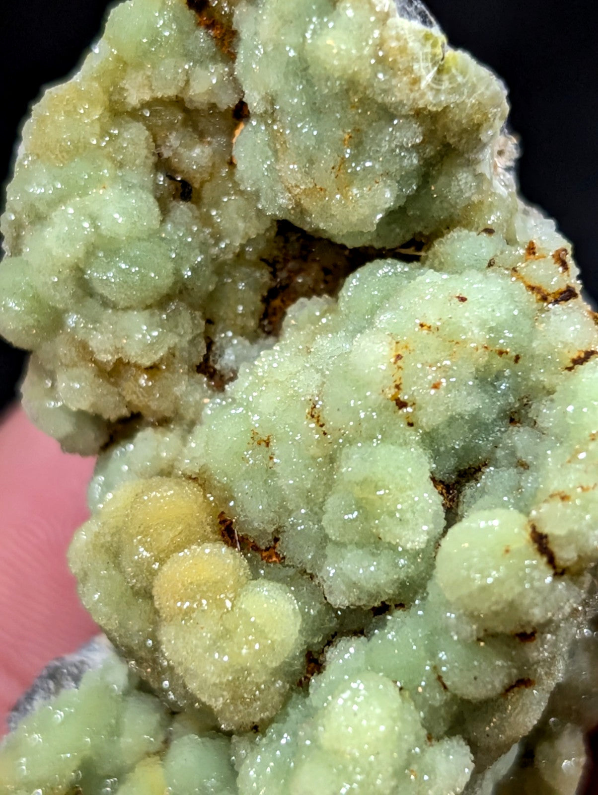 A cluster of translucent, pale green and yellowish crystals with a crystalline, bubbly texture.
