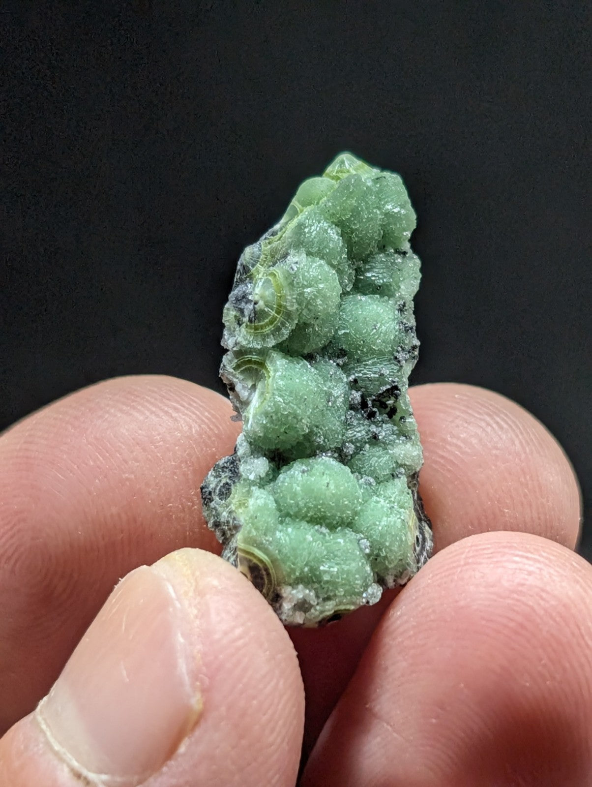 A green, textured mineral specimen with rounded, bubble-like formations and a rough, crystalline surface.
