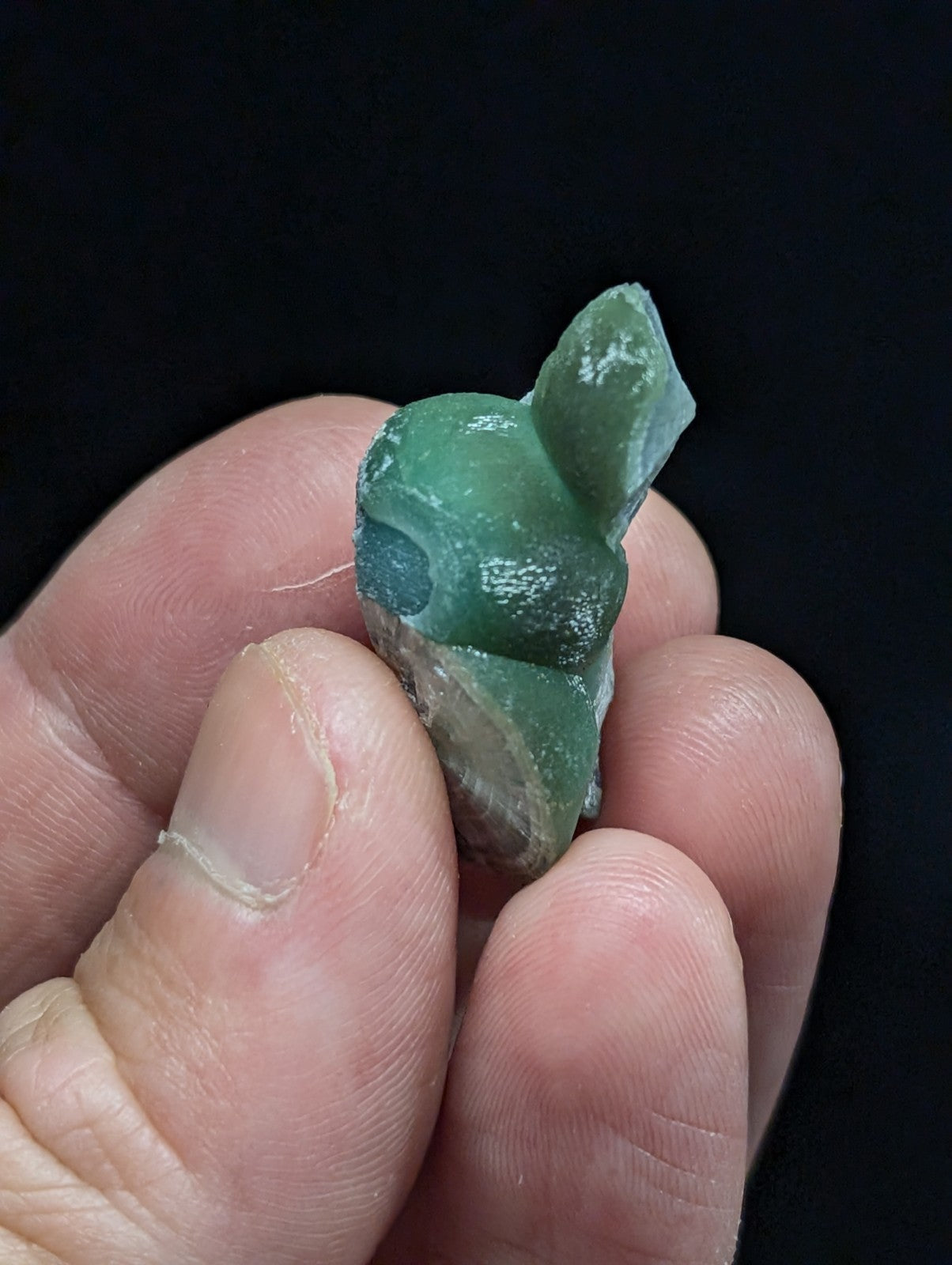 A translucent green, hand-carved figurine with a smooth, slightly glossy surface and subtle white speckles.