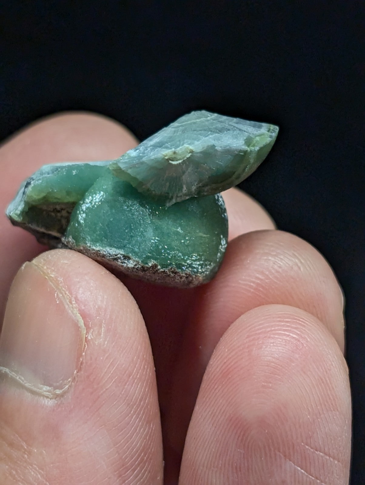 A rough, translucent green jade stone with natural facets and a slightly uneven surface.