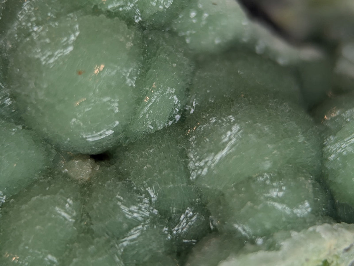A cluster of translucent, pale green mineral crystals with a slightly rough and faceted surface.