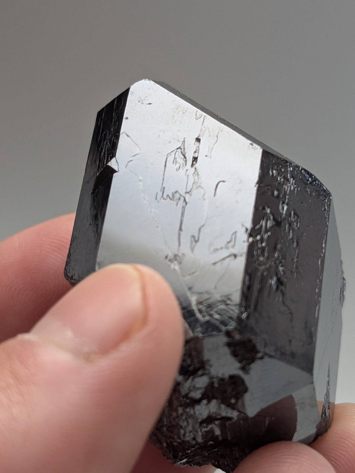 A polished, dark metallic mineral specimen with reflective facets and subtle internal striations.