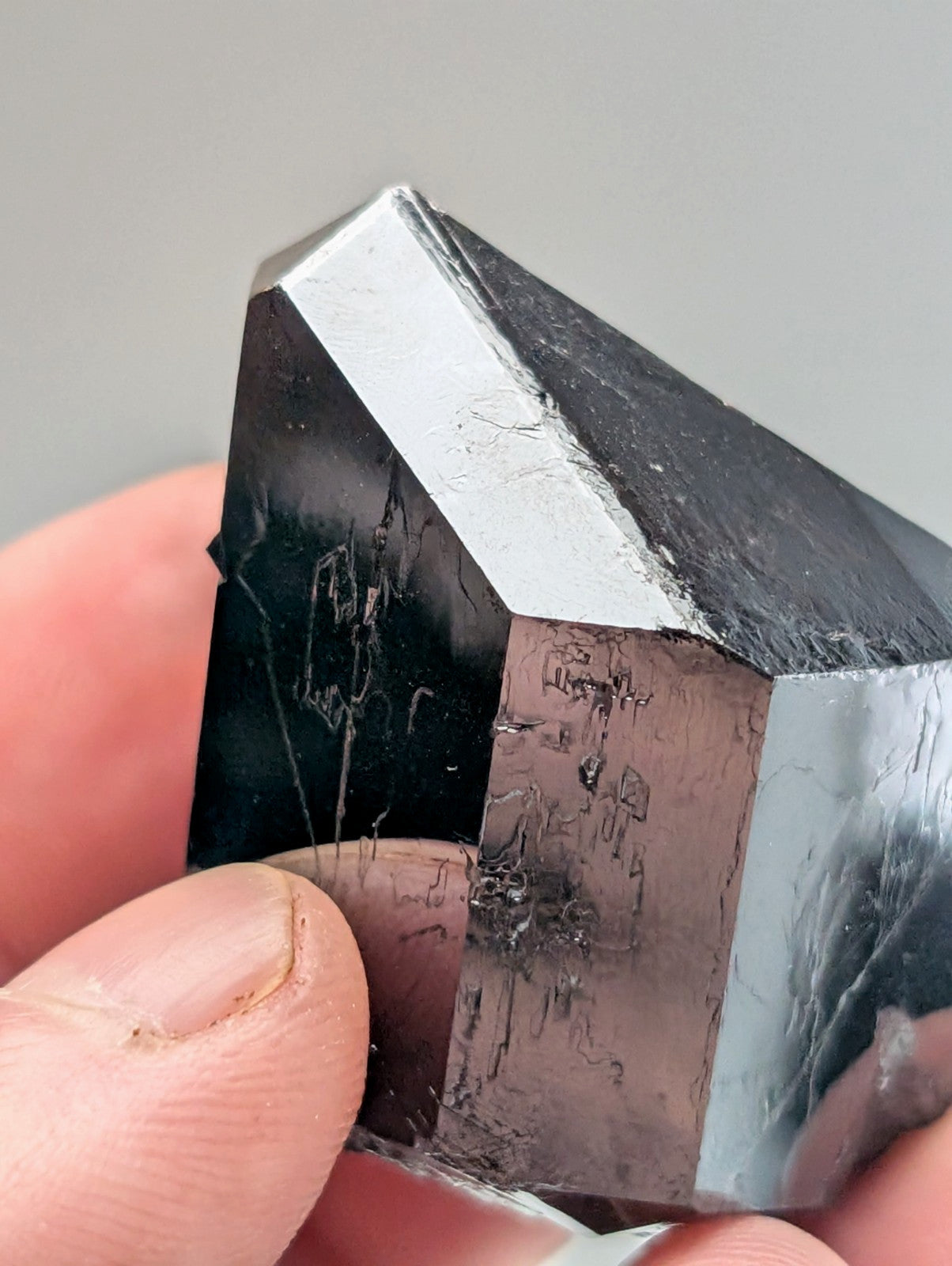 A polished black and silver metallic crystal with a faceted, geometric shape.