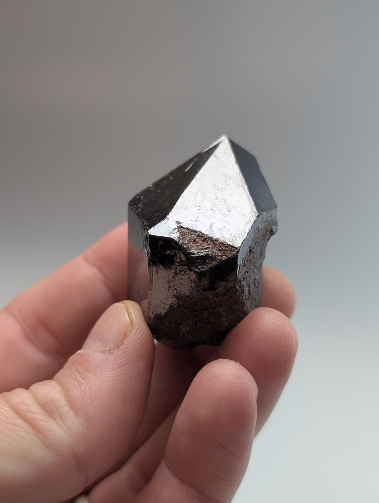 A polished black pyrite crystal with a sharp, geometric point and reflective facets.