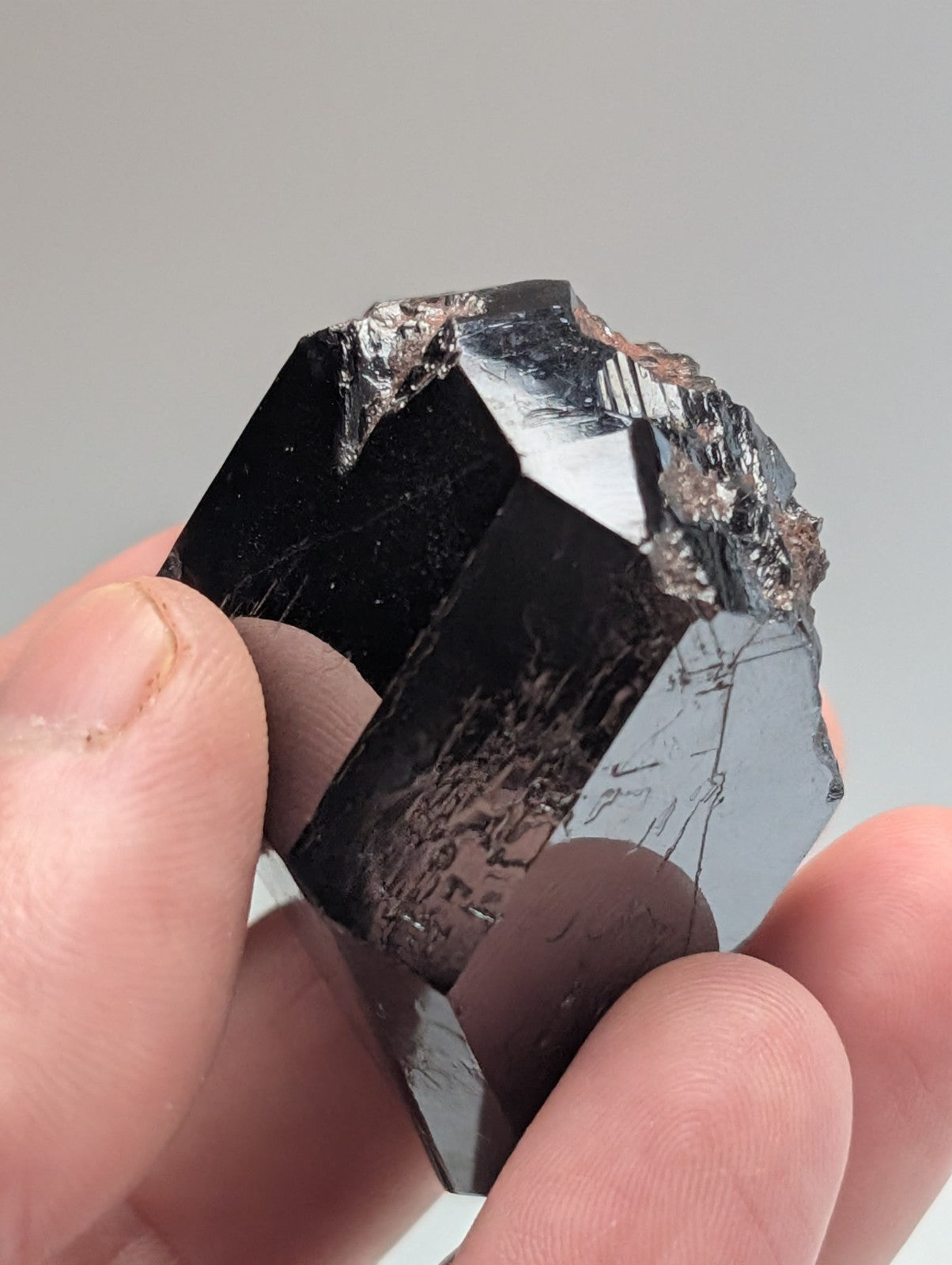 A polished black tourmaline crystal with a faceted, geometric shape and natural mineral inclusions.