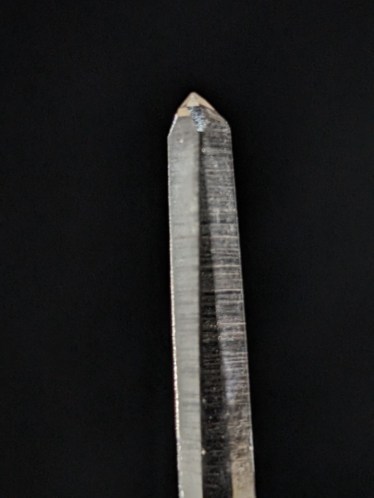 A clear, translucent quartz crystal with a pointed tip and visible internal striations.