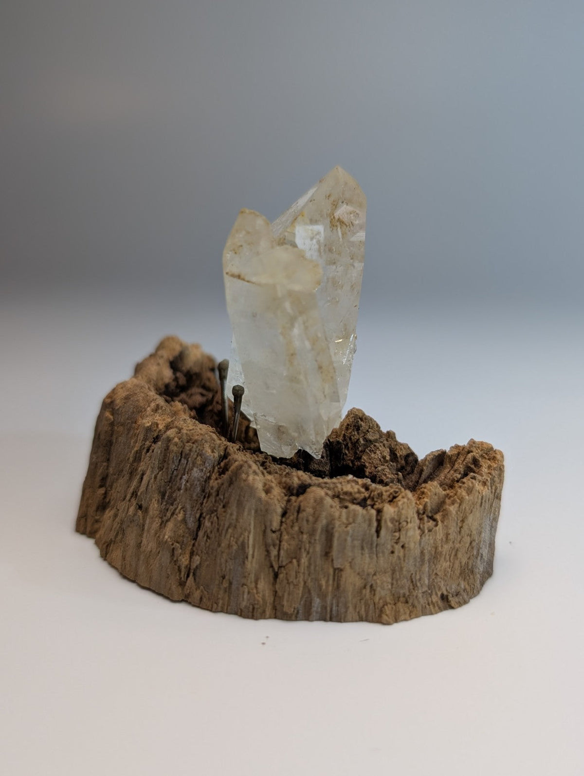 A translucent faceted quartz crystal cluster mounted on a rustic wooden base from garland county arkansas