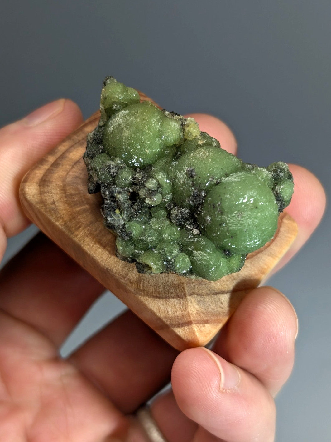 A a+++ museum grade vibrant green wavellite mineral with glossy surface and dark veining on handmade wood stand