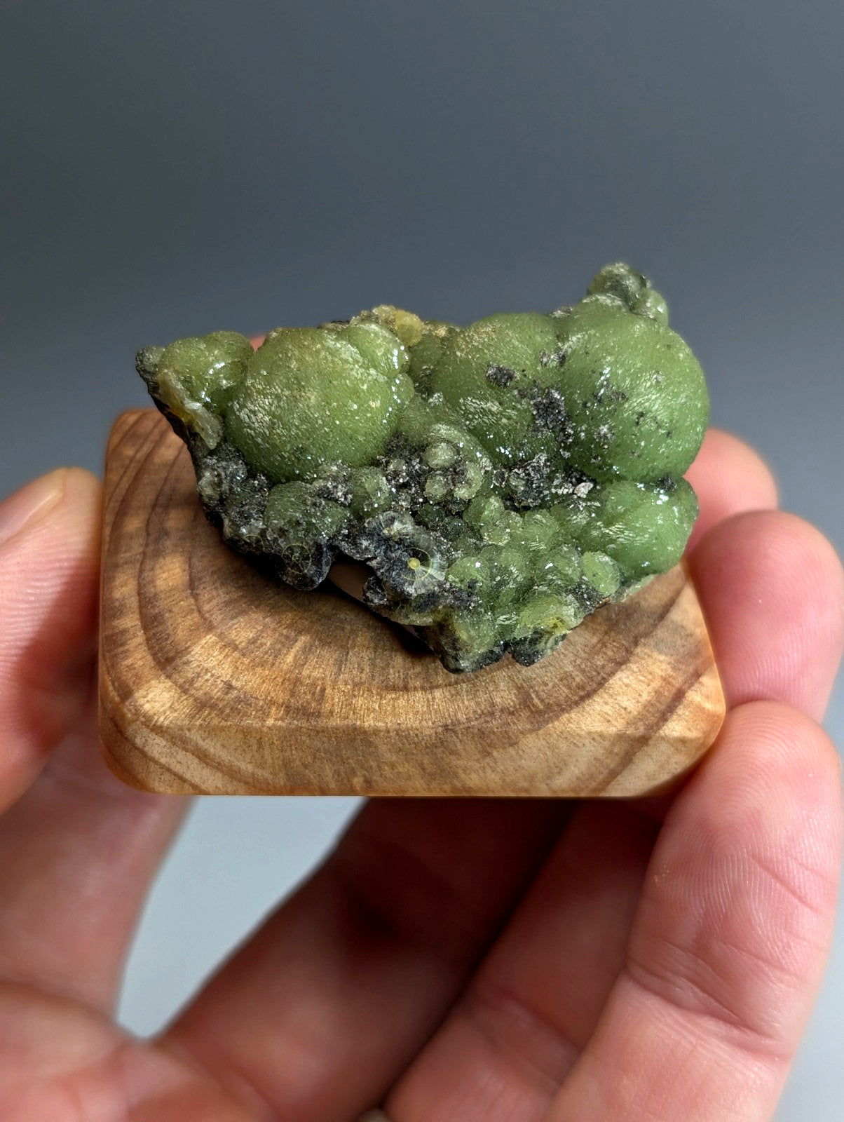 A museum grade A+++ vibrant green wavellite mineral with dark veining on a handmade wood mount from Arkansas