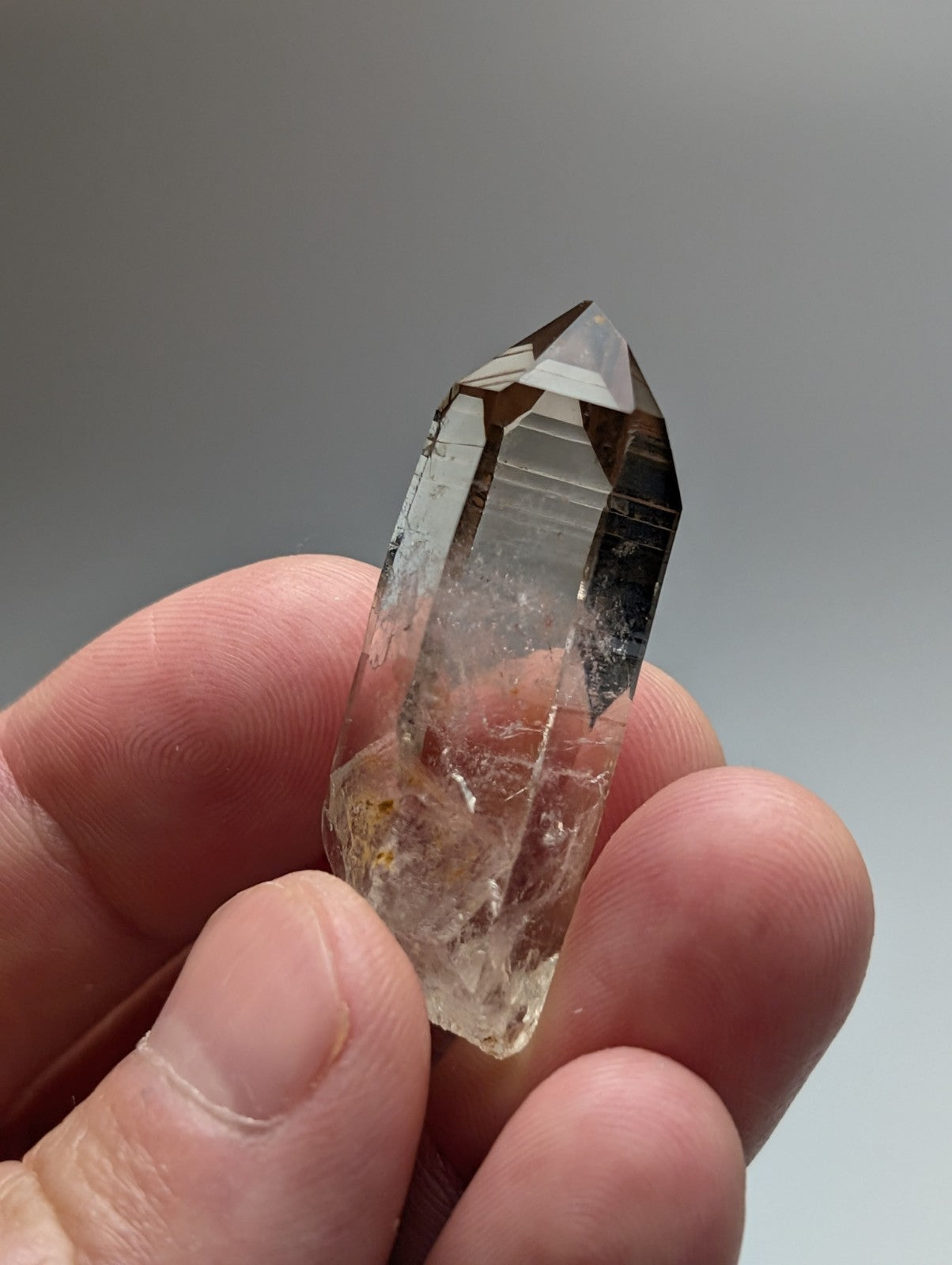 A+++ natural smoky quartz crystal point with translucent smoky color and internal inclusions held between fingers from Garland County Arkansas USA