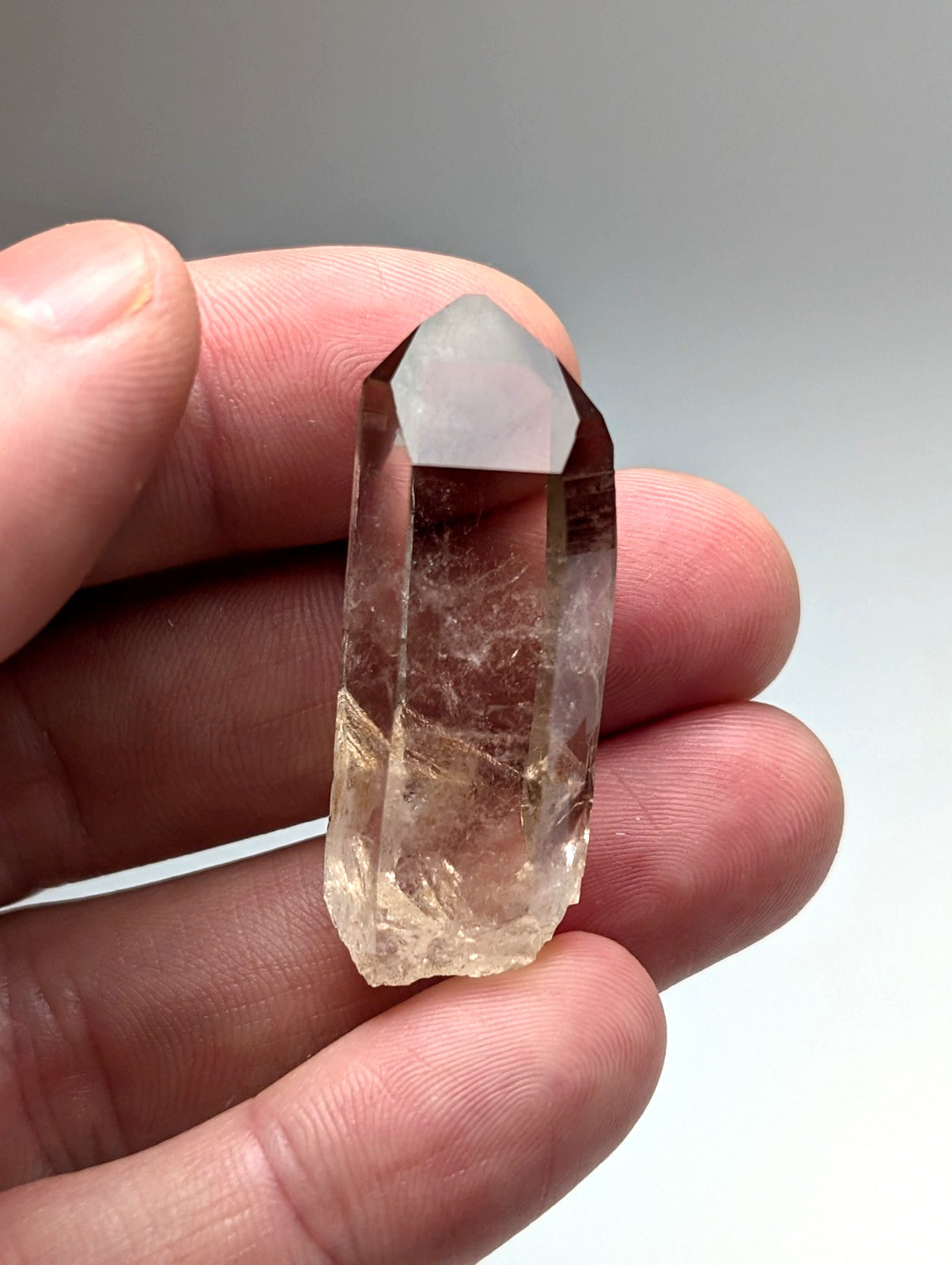 A translucent amber-hued smoky quartz crystal point with natural internal inclusions from garland county arkansas usa