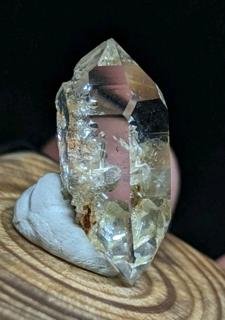 A translucent, faceted quartz crystal with natural inclusions and a slightly yellowish tint, displayed on a white ceramic stand.
