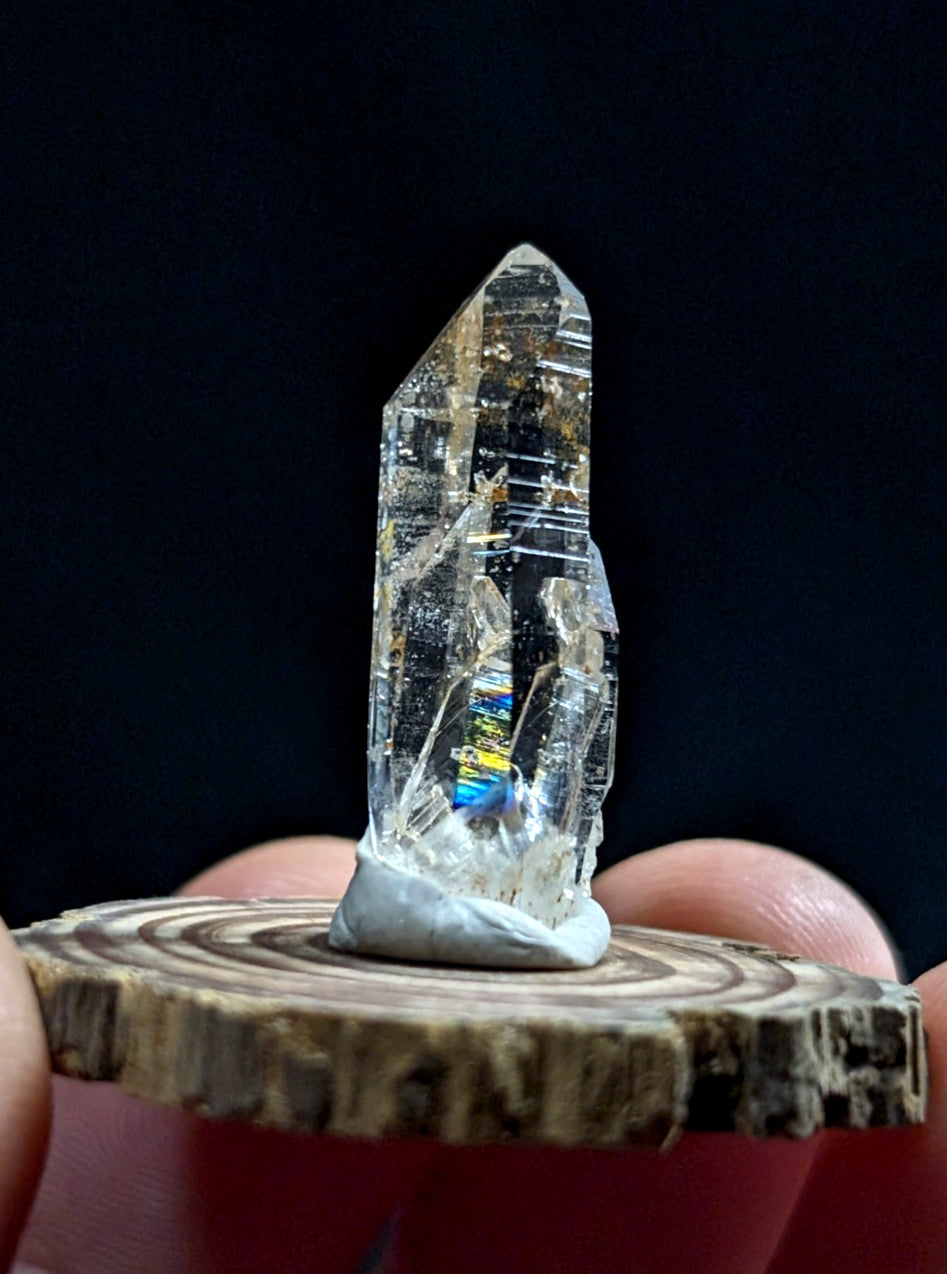 A clear, translucent quartz crystal with internal rainbow reflections and visible striations.