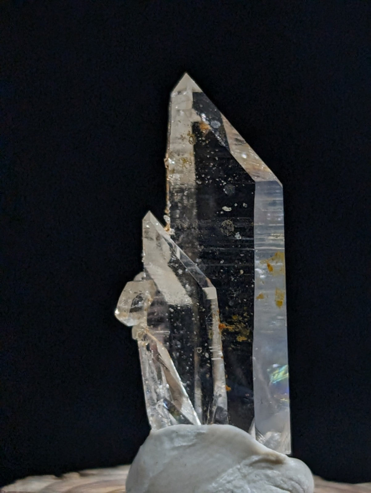 A clear quartz crystal cluster with golden inclusions and a polished, faceted base.