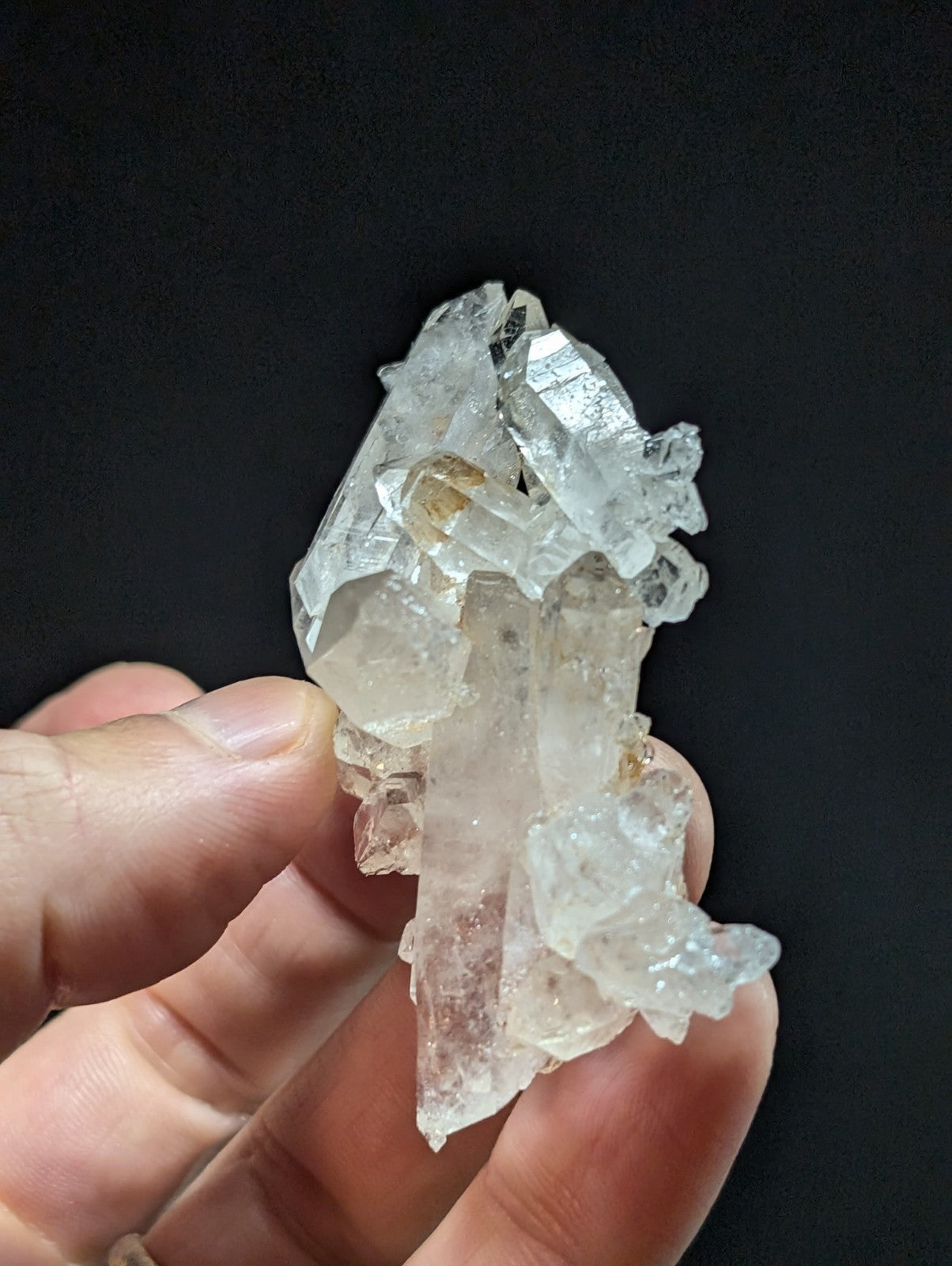 A translucent, clear quartz crystal cluster with sharp facets and subtle golden inclusions.