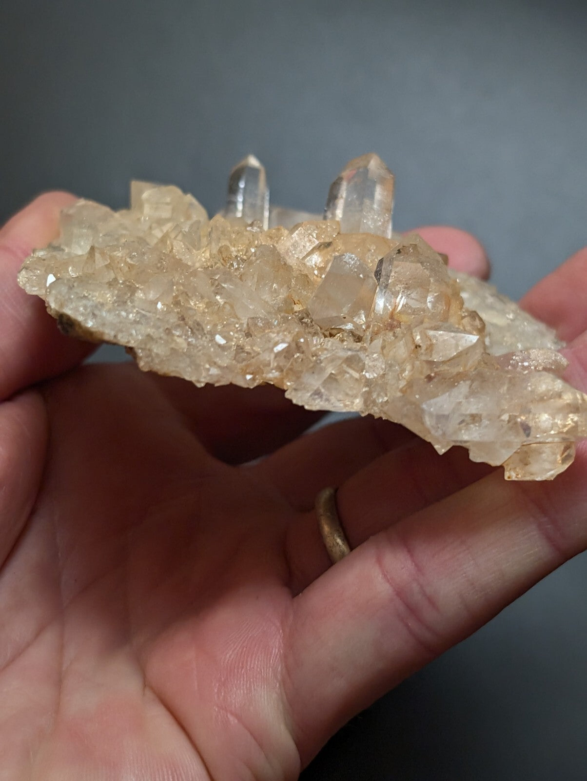 A translucent, golden-hued quartz crystal cluster with sharp, pointed formations and a rough-textured base.