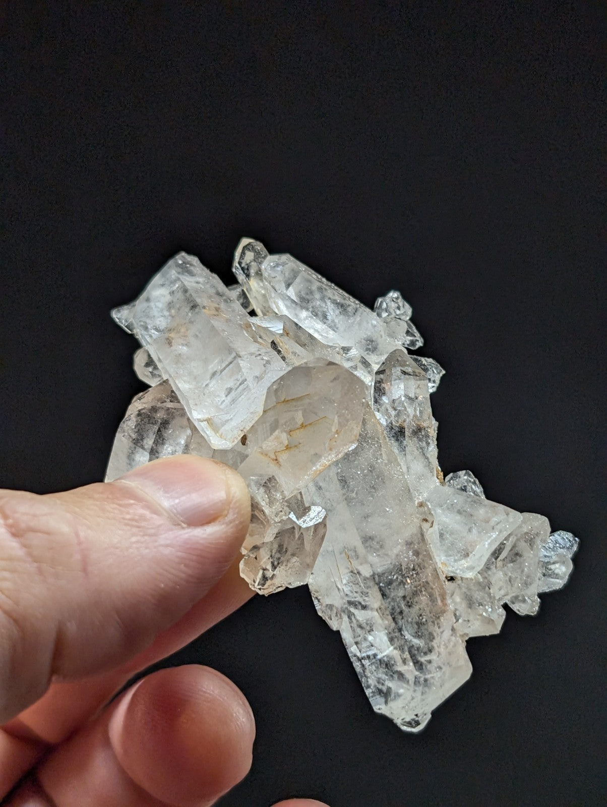 A cluster of clear, translucent quartz crystals with sharp edges and natural facets.