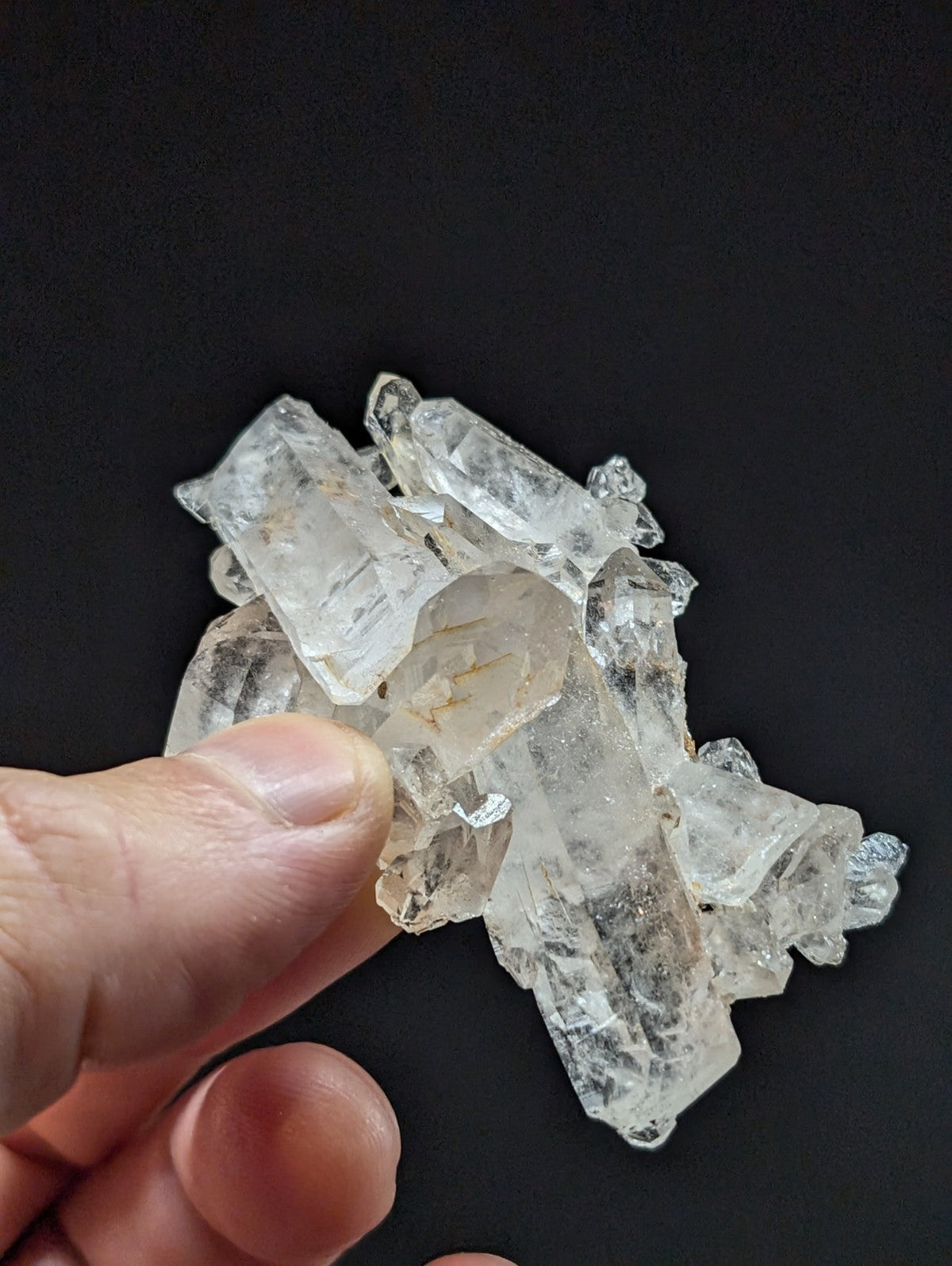 A cluster of clear, translucent quartz crystals with sharp edges and natural facets.