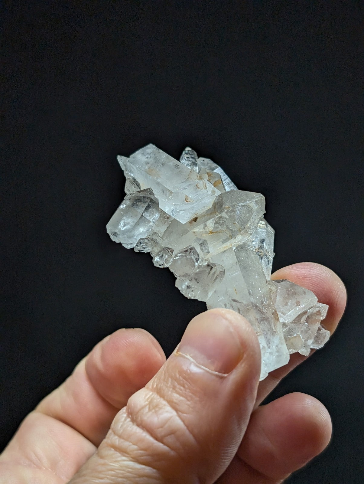 A translucent, clear quartz crystal cluster with sharp, angular facets and a natural, irregular formation.