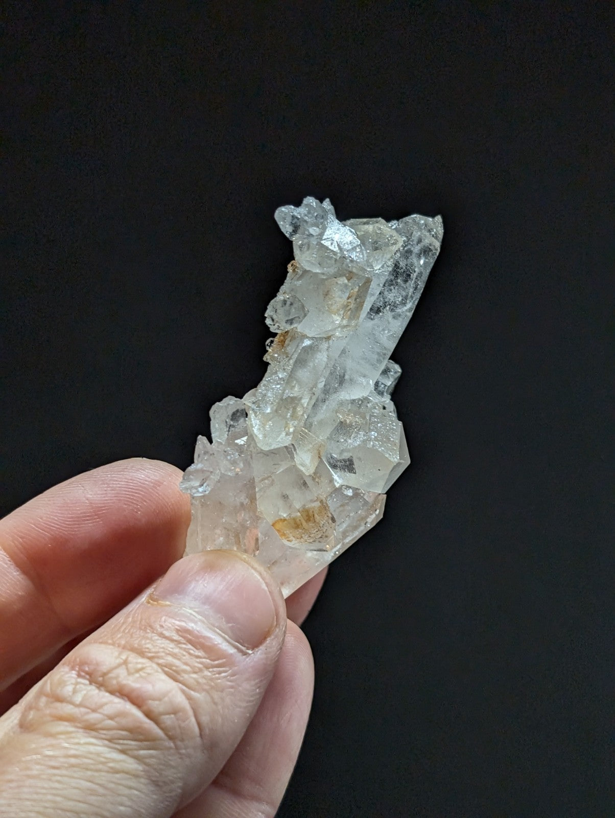 A translucent, clear quartz crystal cluster with jagged edges and subtle golden inclusions.