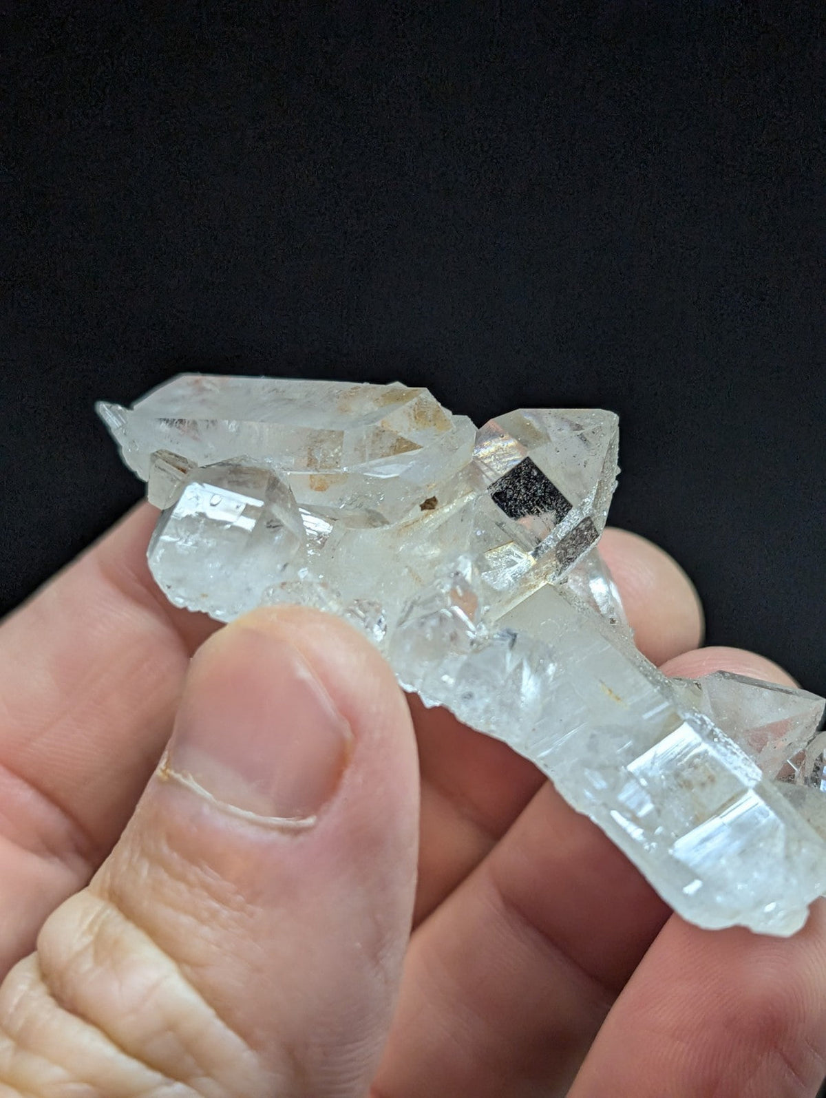 A translucent, clear quartz crystal cluster with sharp geometric facets and subtle internal inclusions.