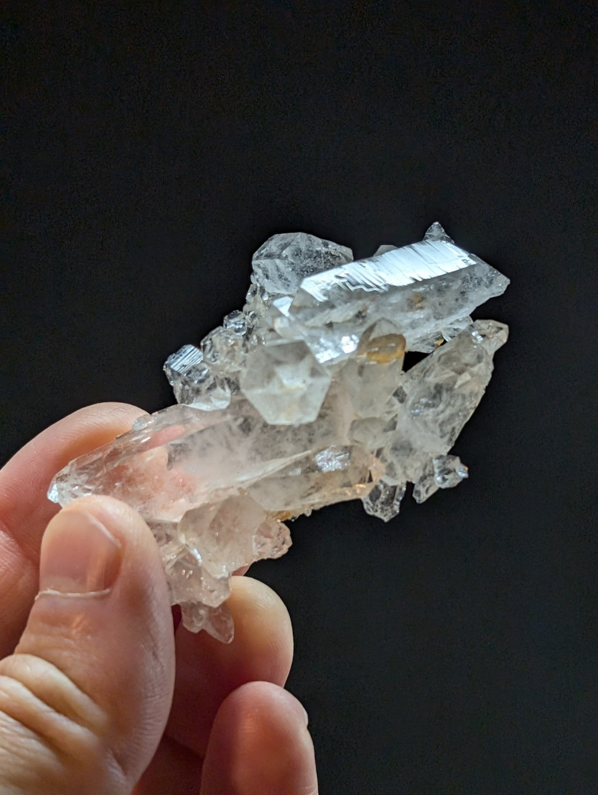 A translucent quartz crystal cluster with clear, faceted points and subtle golden inclusions.