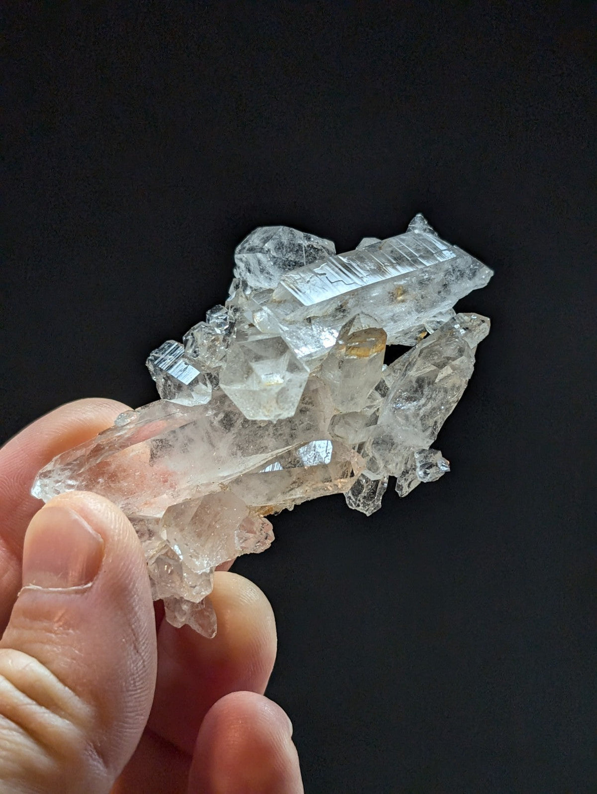 A translucent, clear quartz crystal cluster with sharp facets and a natural, irregular formation.