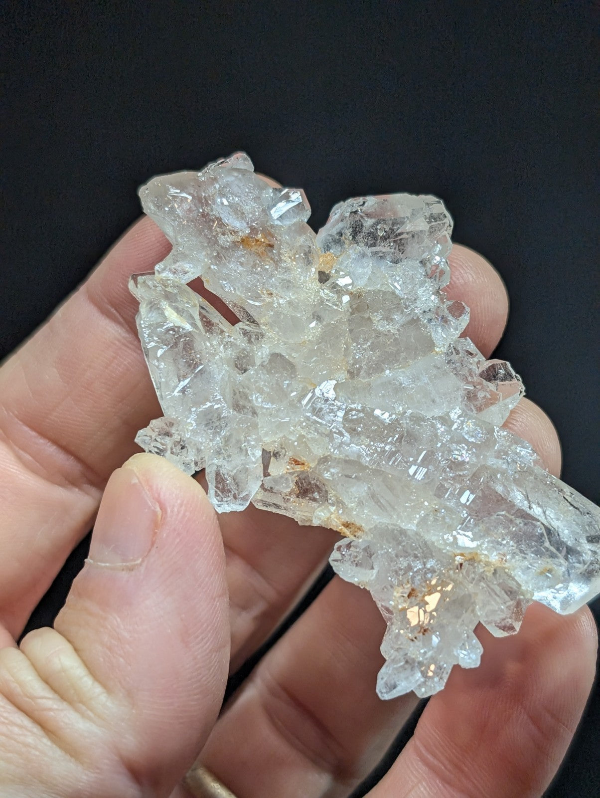 A cluster of clear, faceted quartz crystals with subtle golden inclusions.