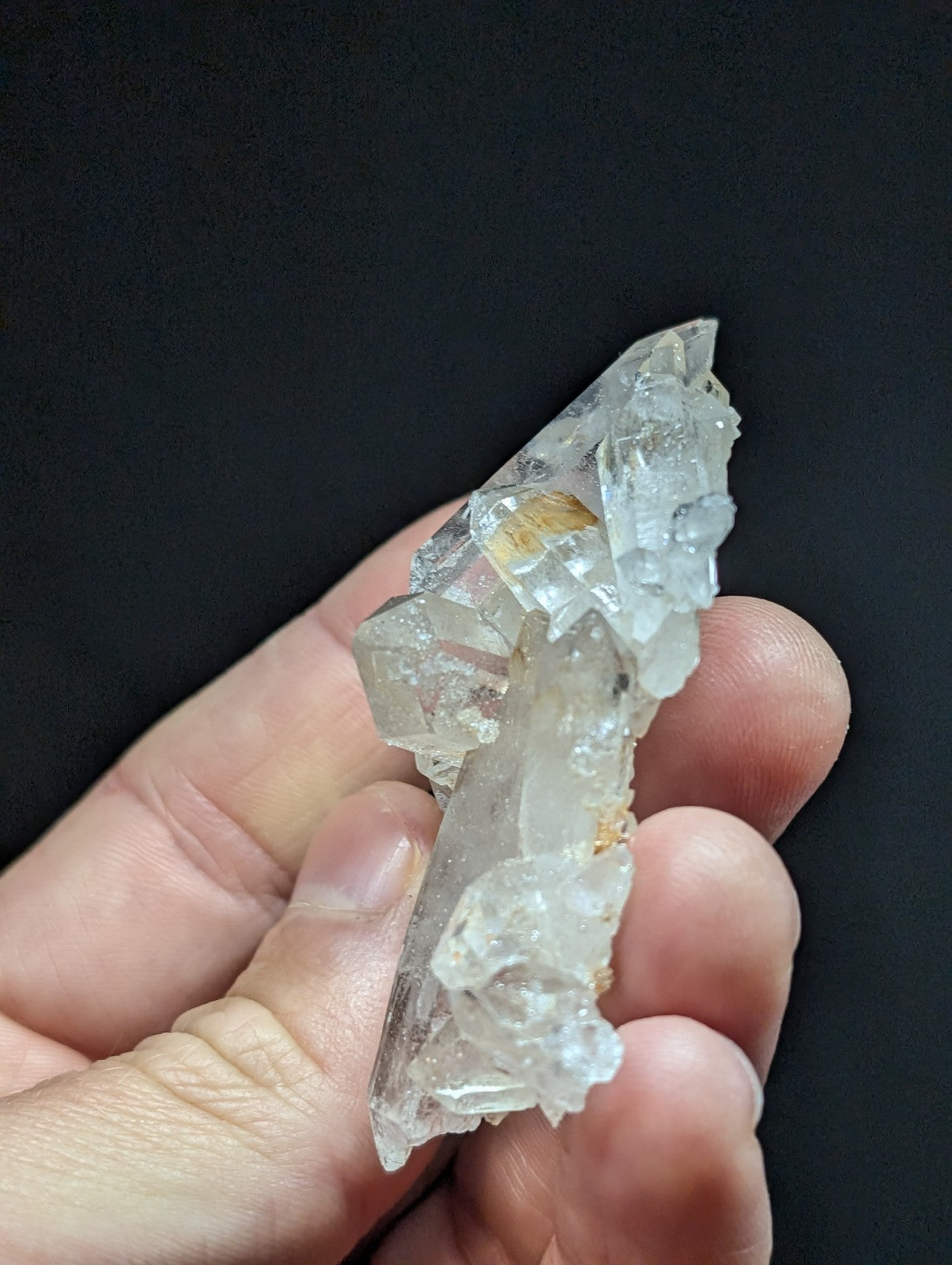 A translucent, clear quartz crystal cluster with subtle golden inclusions and jagged edges.
