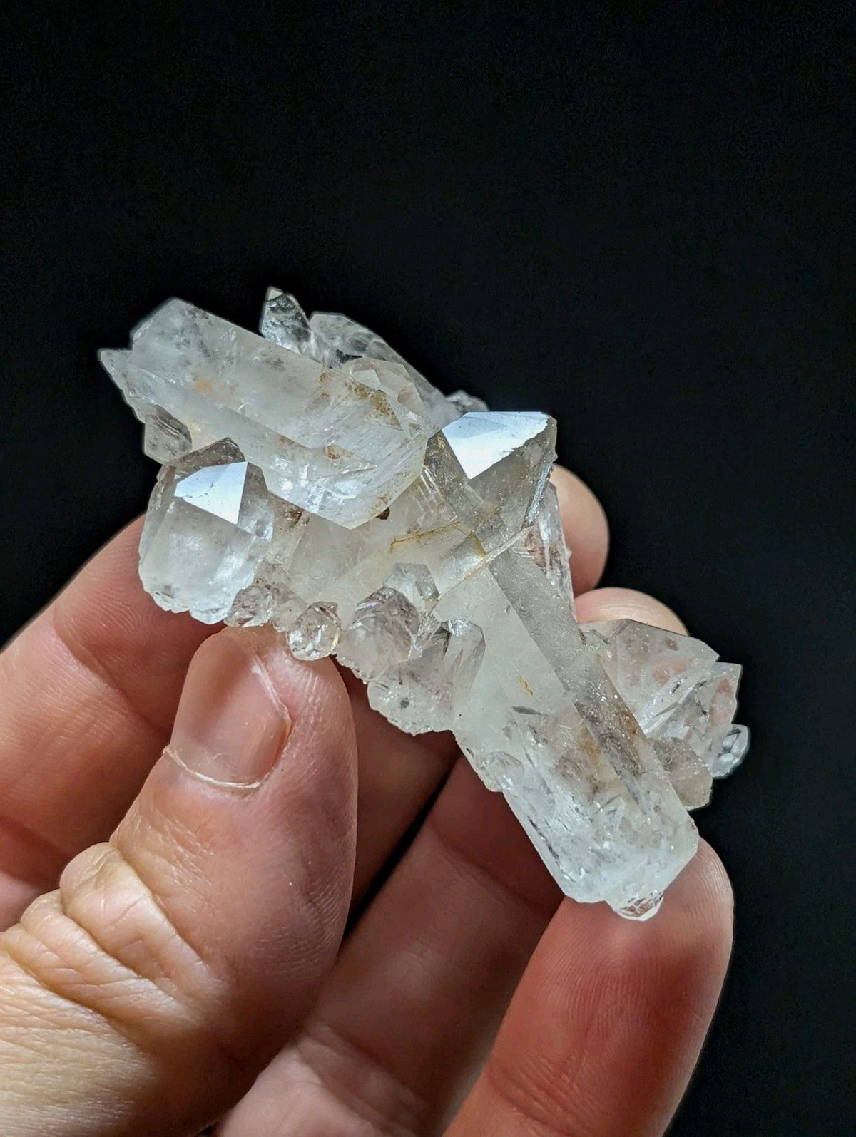 A cluster of clear, translucent quartz crystals with sharp facets and natural imperfections.