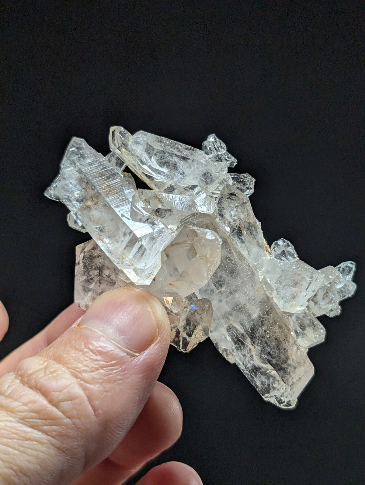 A cluster of clear, translucent quartz crystals with sharp edges and natural facets.