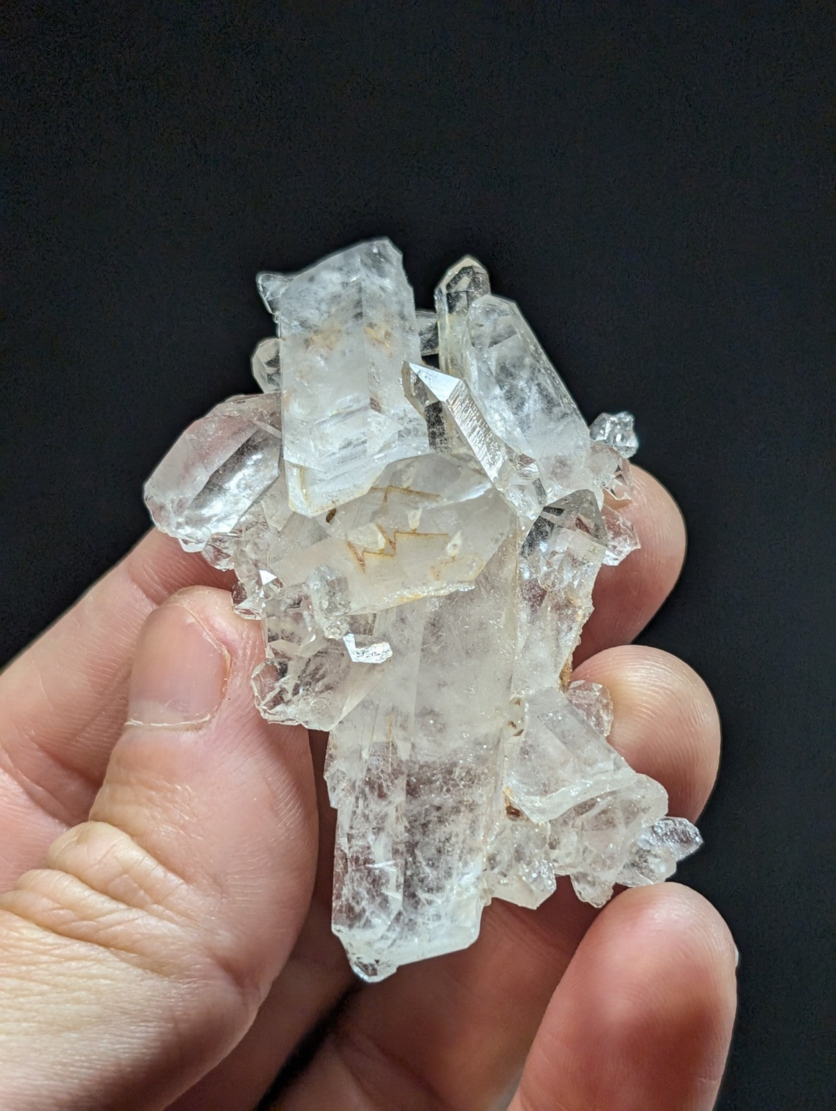 A cluster of clear, translucent quartz crystals with sharp edges and natural inclusions.