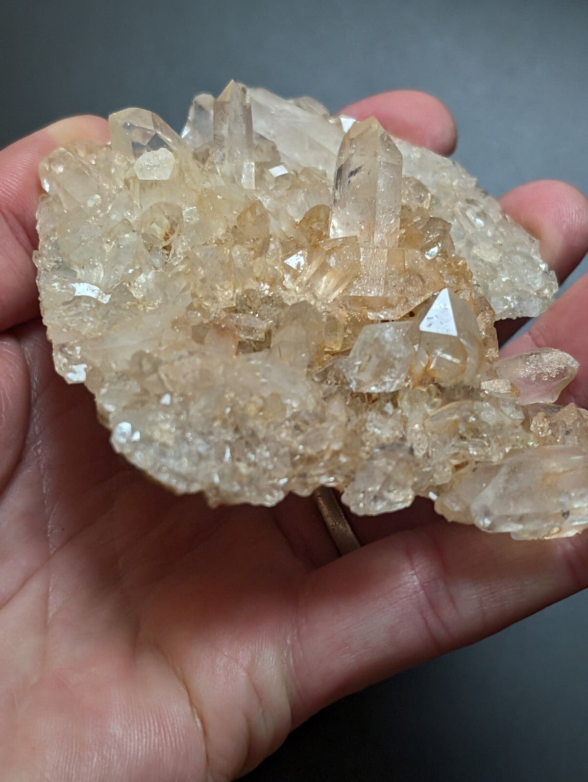 A cluster of translucent, golden-hued quartz crystals with sharp, faceted points and a natural, earthy texture.