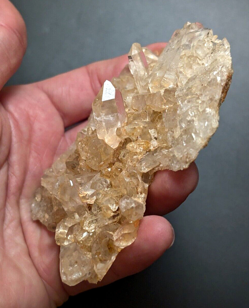 A translucent golden-yellow crystal cluster with sharp, faceted points and a rough, earthy base.