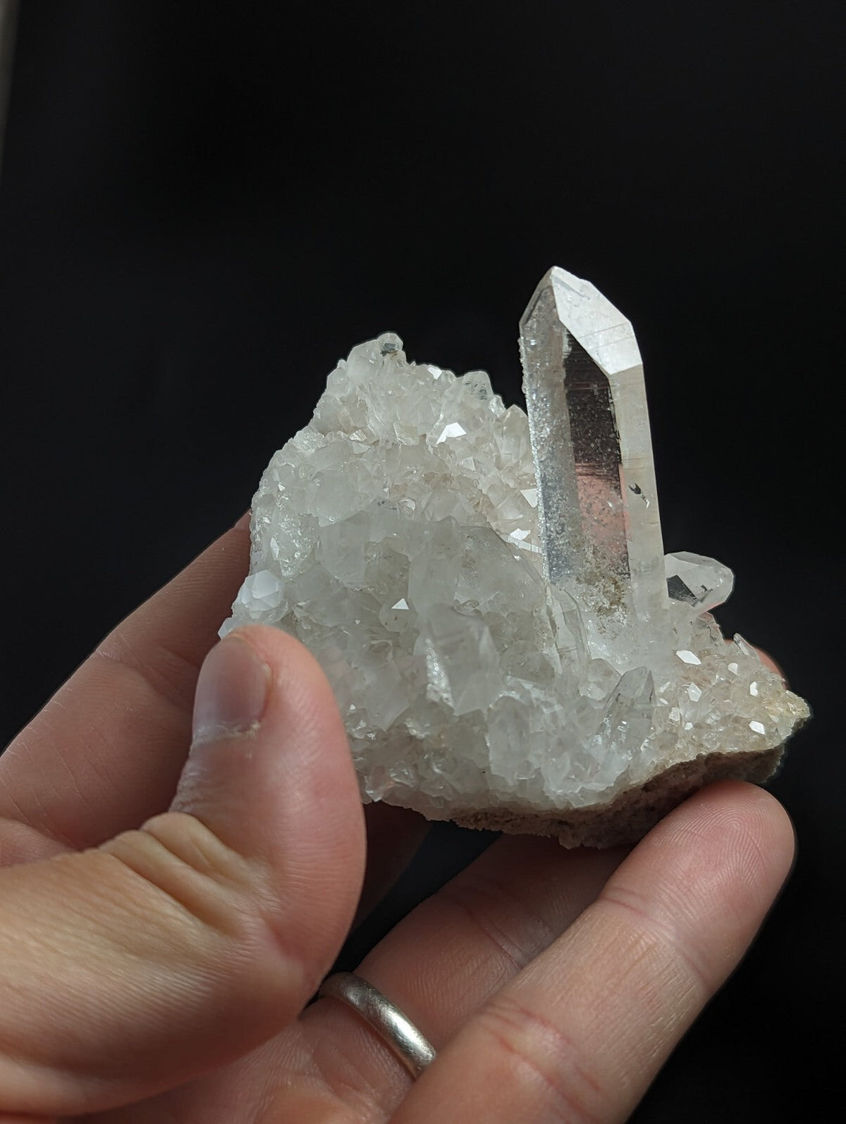 A translucent white quartz crystal cluster with a prominent, clear point emerging from a dense mass of smaller crystals.
