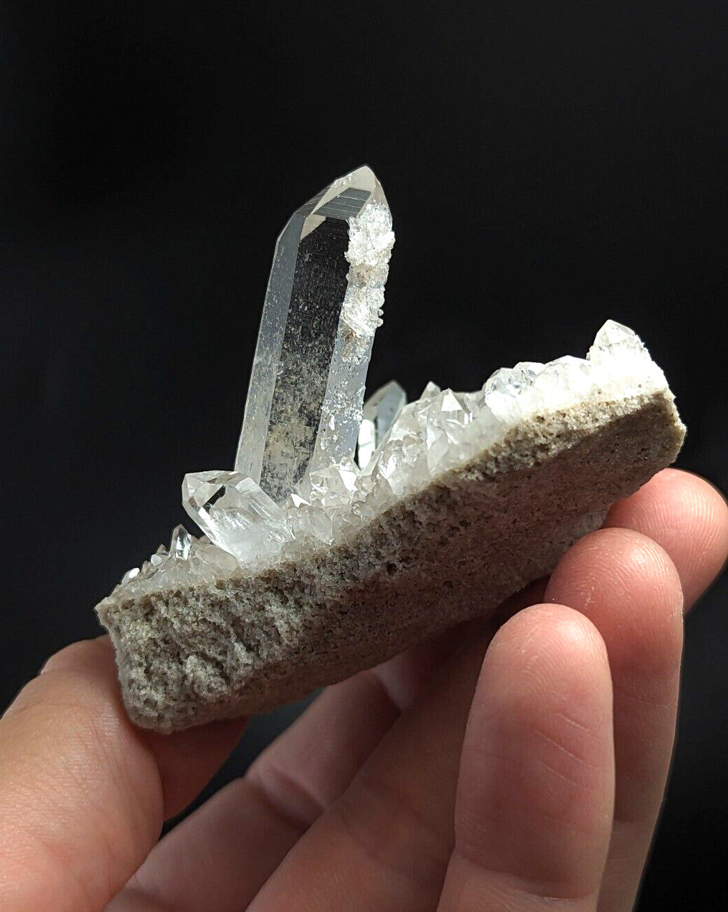 A translucent quartz crystal cluster emerging from a rough, gray rock matrix.