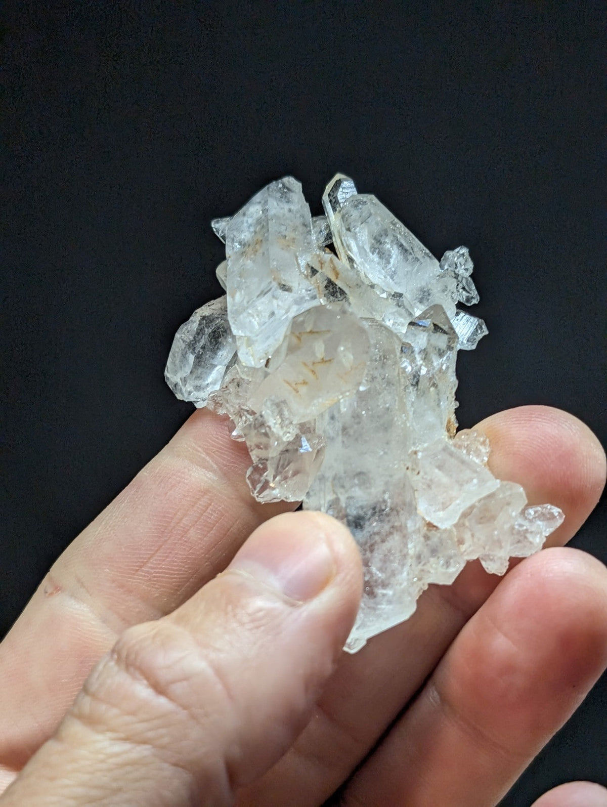 A cluster of clear, translucent quartz crystals with sharp edges and natural facets.