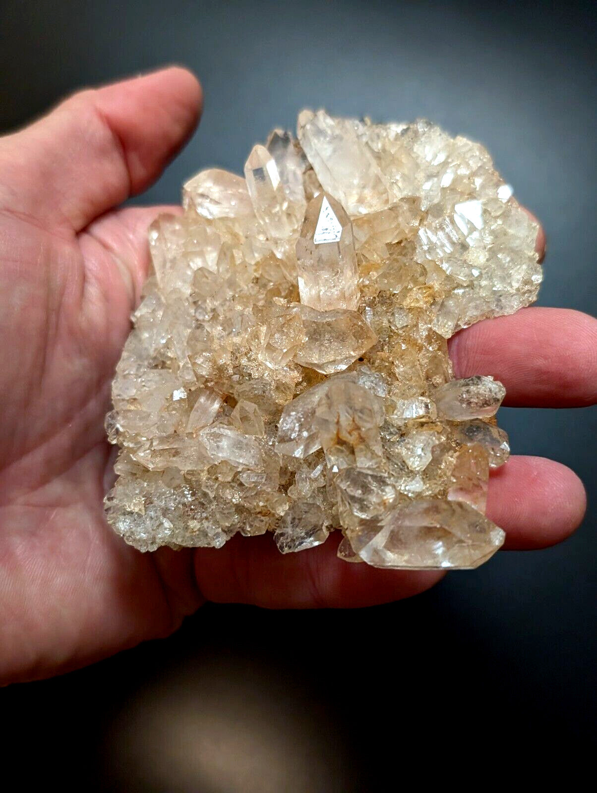 A cluster of translucent, golden-hued quartz crystals with sharp, faceted points and a rough, natural texture.