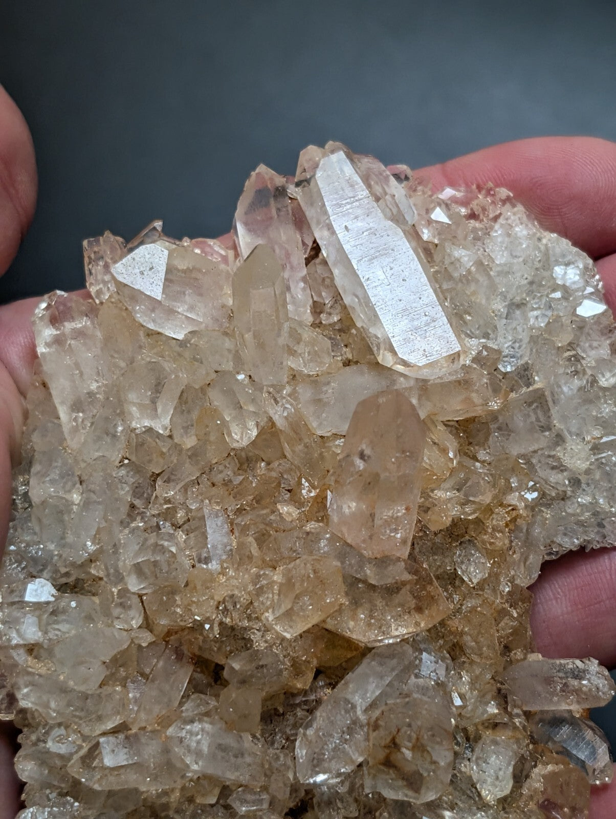 A cluster of translucent, amber-hued quartz crystals with sharp, faceted edges and a natural, earthy base.