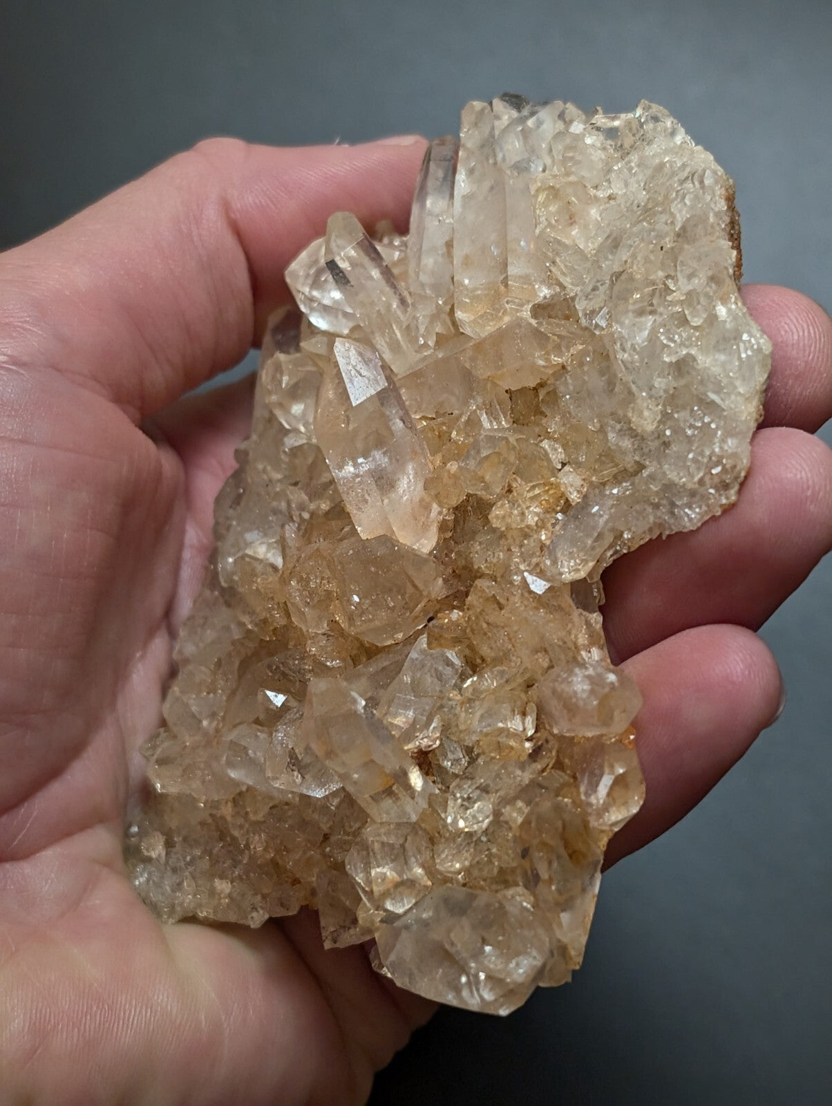 A translucent, golden-hued quartz crystal cluster with sharp, faceted points and a rough, natural base.