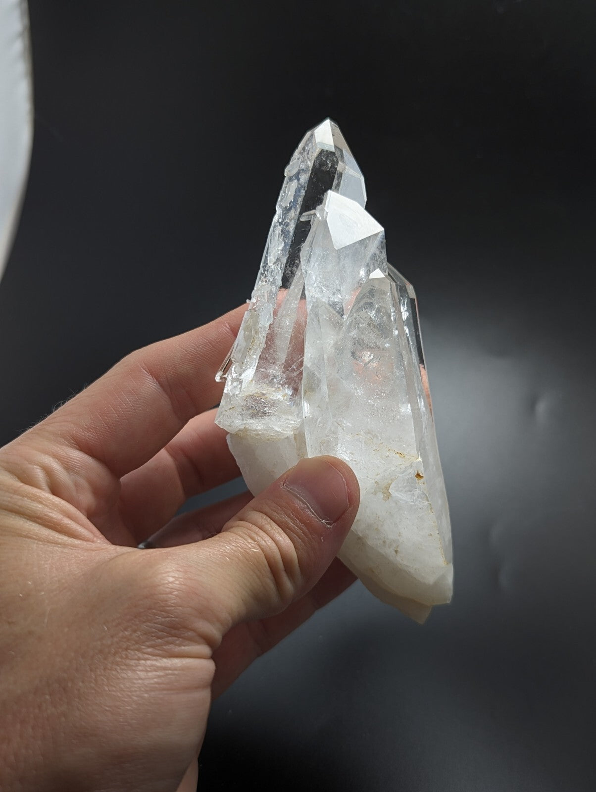 A clear, translucent quartz crystal cluster with sharp, pointed facets and a slightly cloudy base.