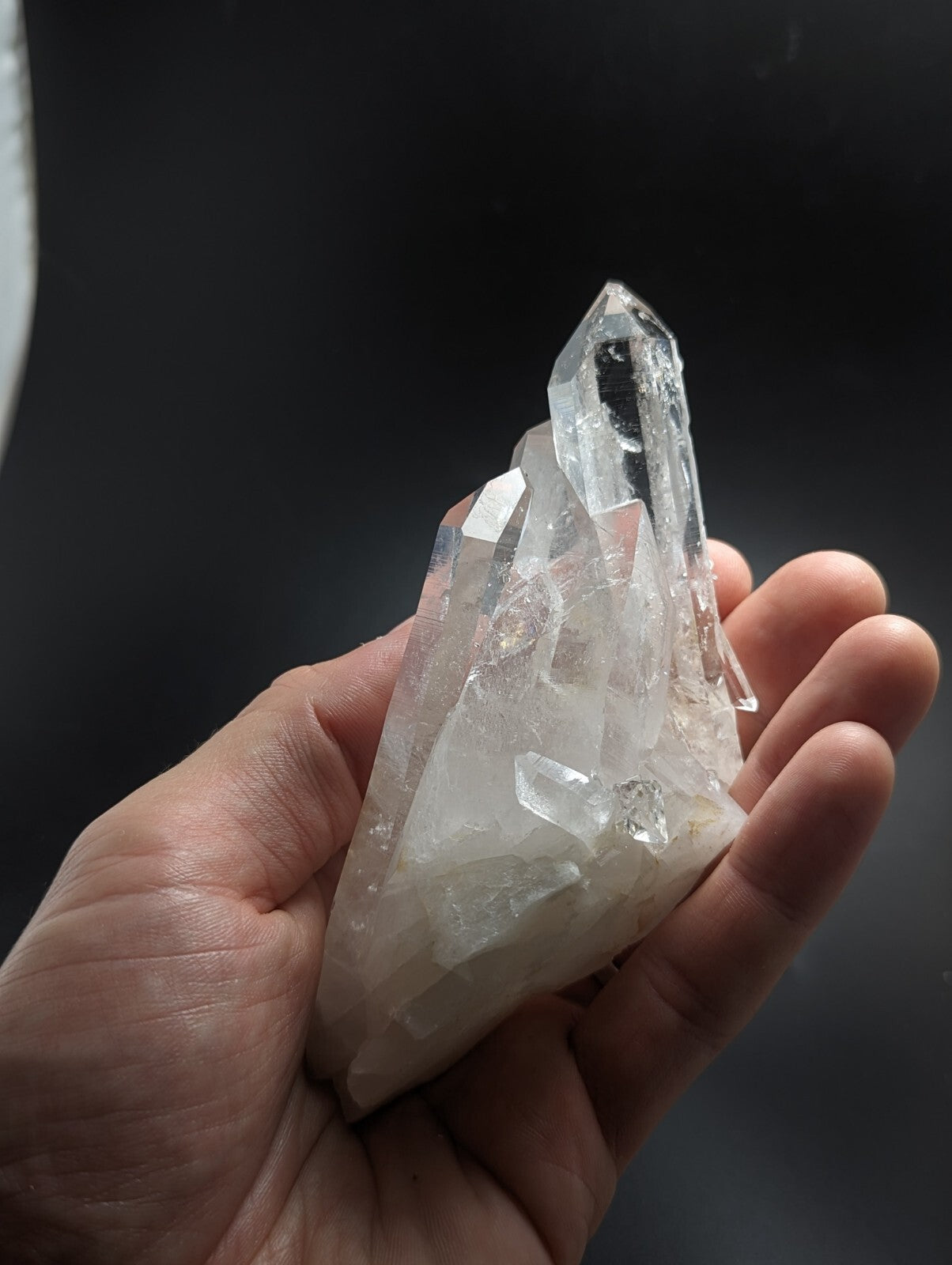 A clear, translucent quartz crystal cluster with sharp facets and a pointed tip.