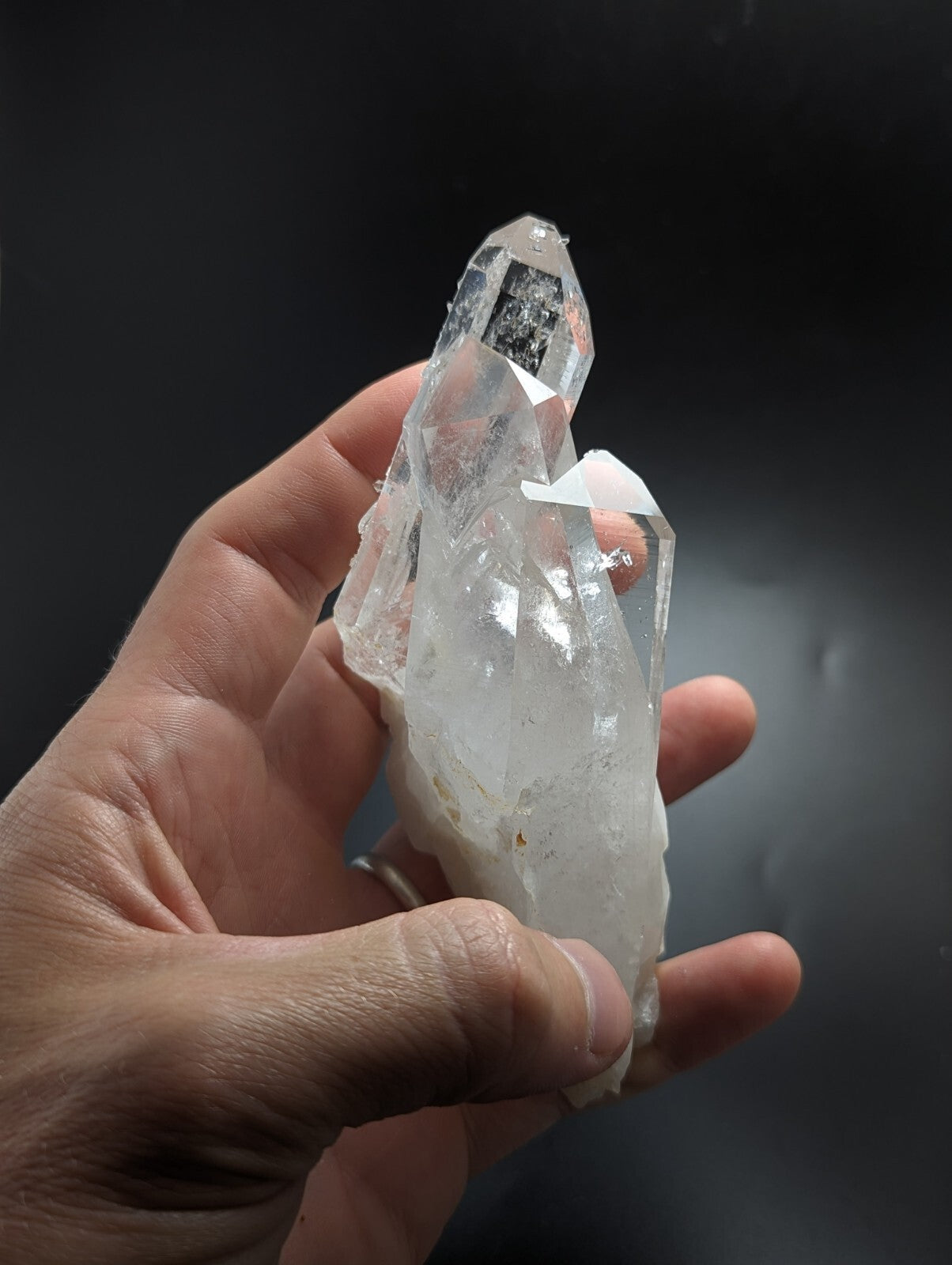 A translucent, clear quartz crystal cluster with sharp geometric facets and a pointed tip.