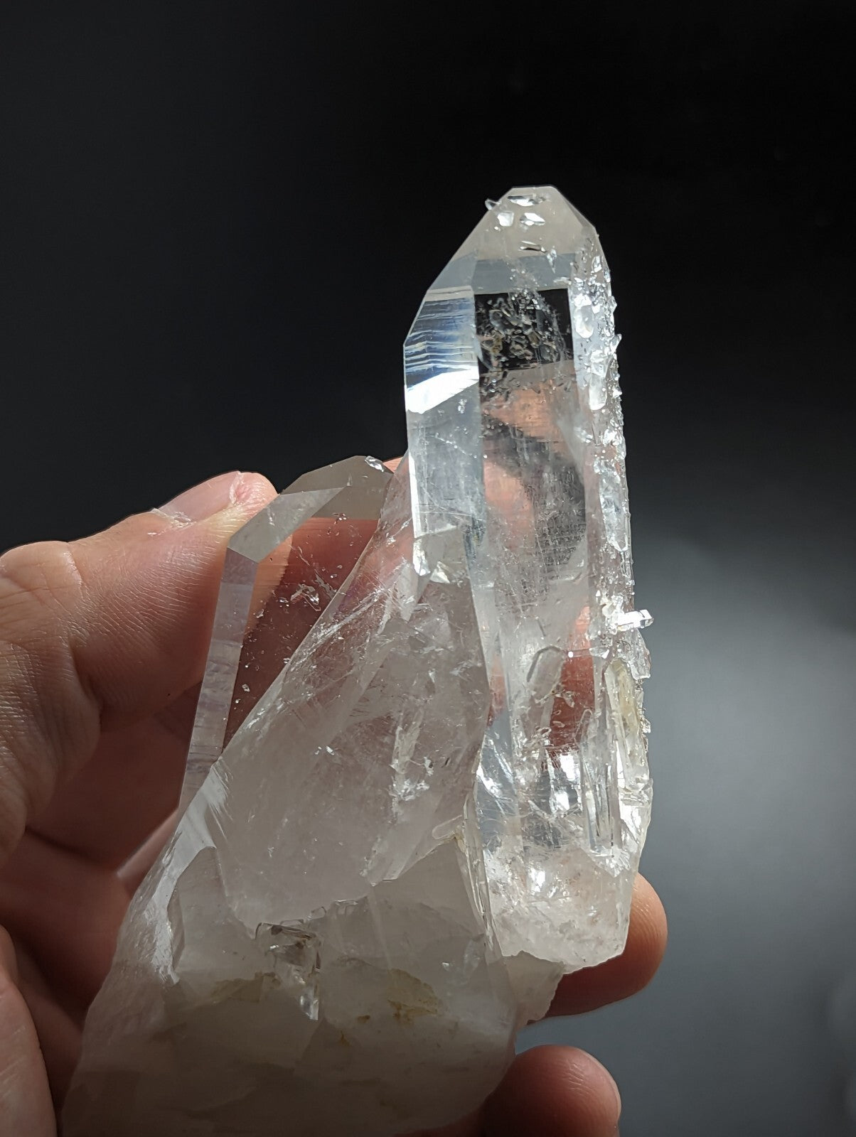 A clear, translucent quartz crystal cluster with sharp facets and a natural, jagged formation.