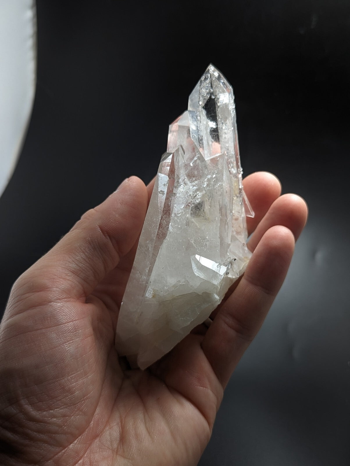 A translucent, clear quartz crystal with a pointed tip and faceted surfaces.