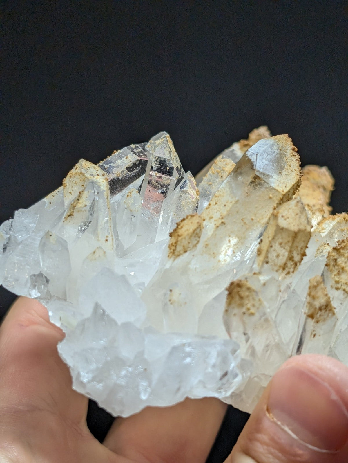 A translucent white quartz crystal cluster with sharp, faceted points and golden-brown mineral residue clinging to its surface.