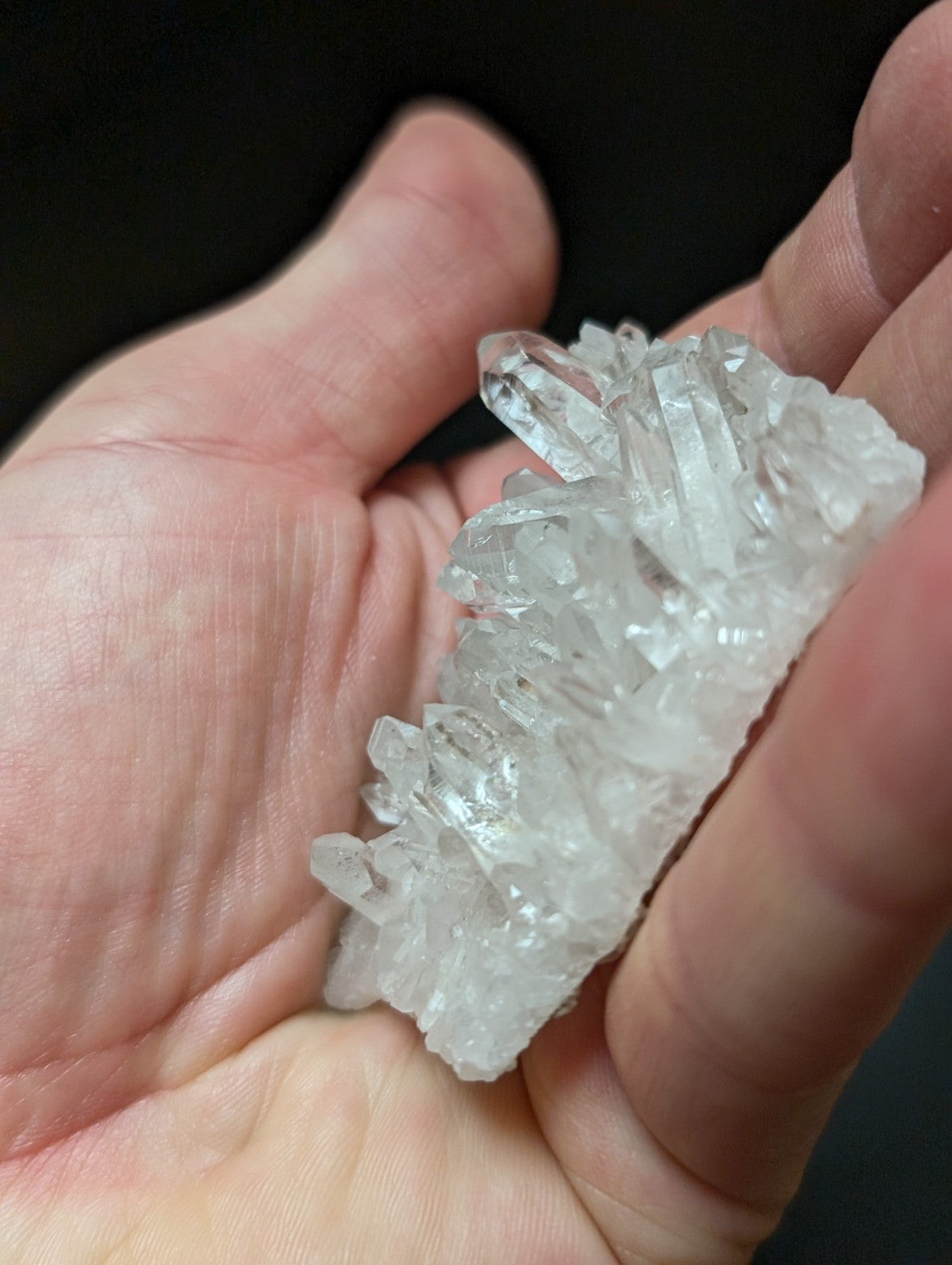 A translucent, clear quartz crystal cluster with sharp, pointed facets and a natural, irregular formation.