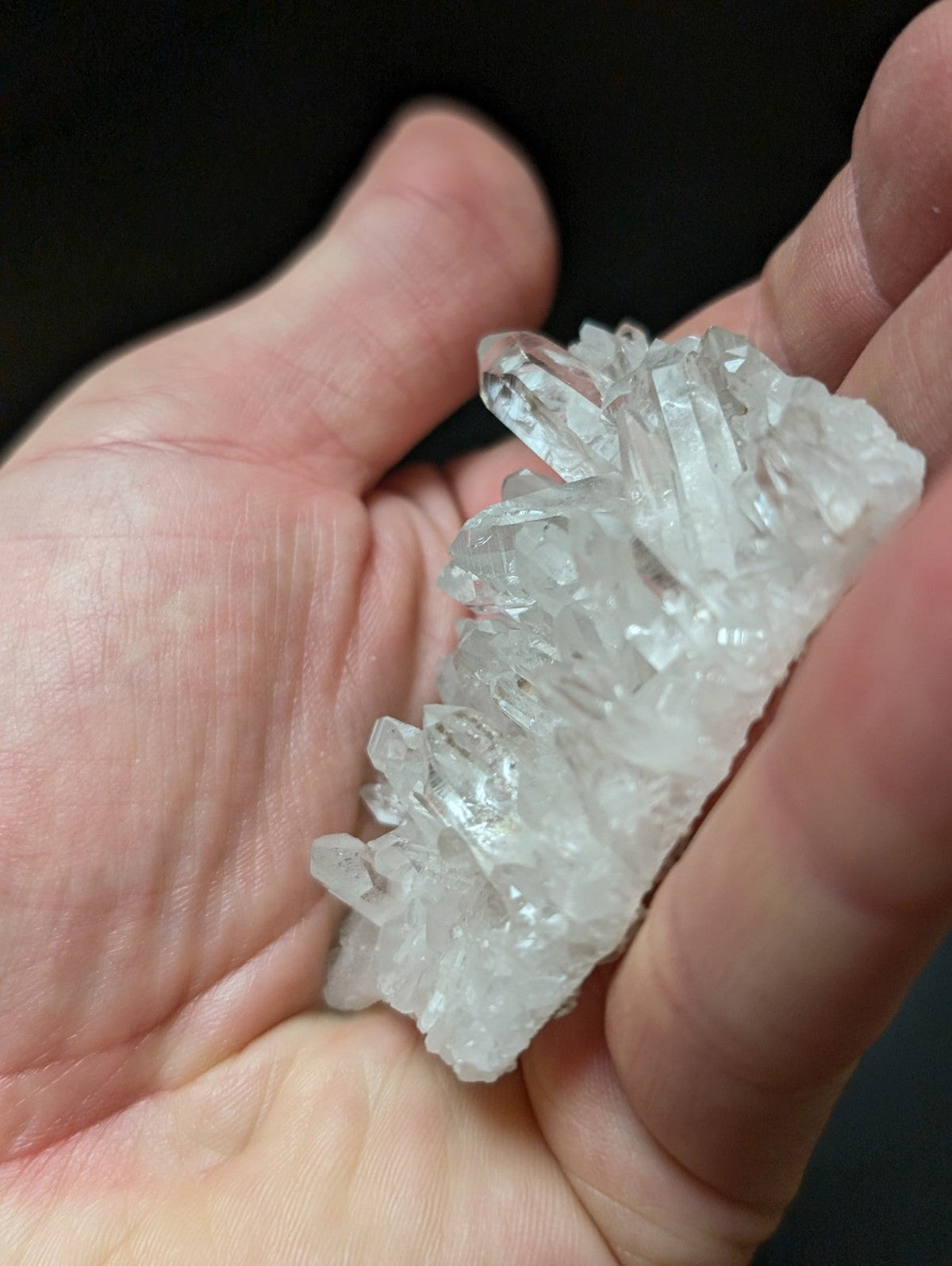 A translucent, clear quartz crystal cluster with sharp, pointed facets and a natural, irregular formation.